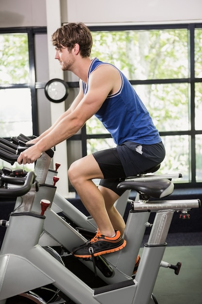 Uomo che lavora su cyclette a lezione di spinning