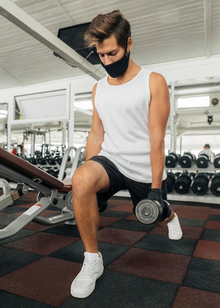 Foto uomo che lavora in palestra con mascherina medica