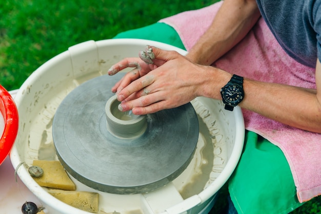 Man working on the potter's wheel. Hands sculpts a cup from clay pot. Workshop on modeling on the potter's wheel.