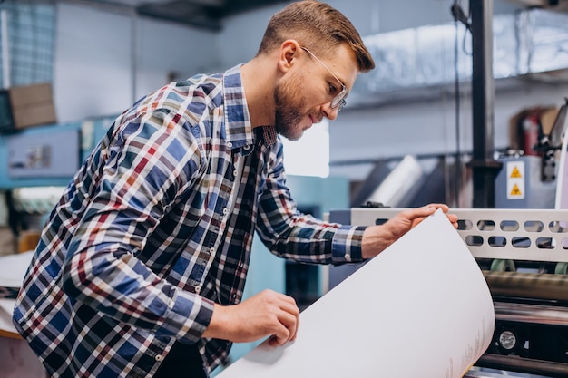 man working in printing house with paper and paints