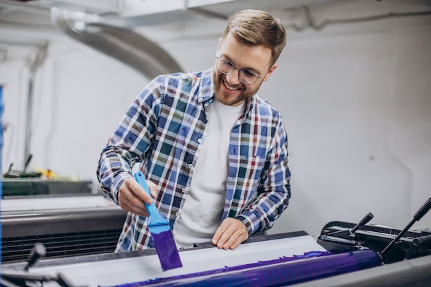 Man working in printing house with paper and paints