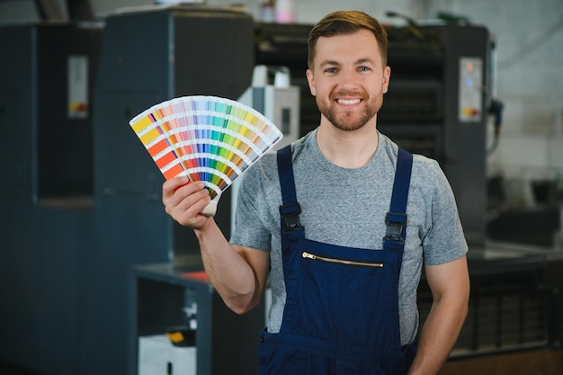 Man working in printing house with paper and paints