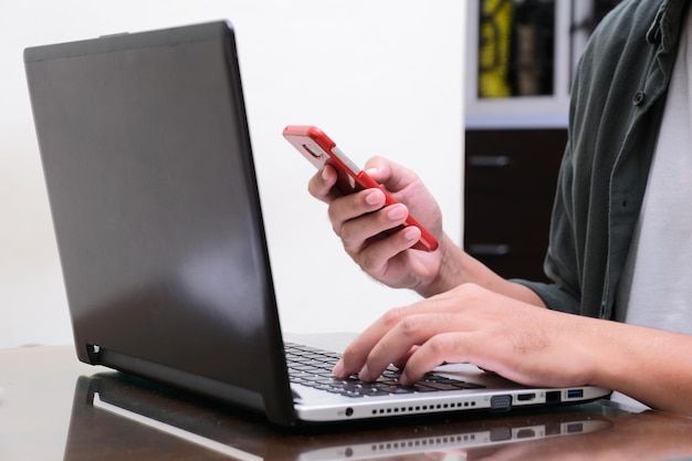 Photo a man working using his mobile phone and laptop focus on hand