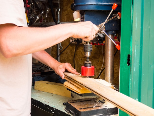 Man working on vertical drilling machine in his workshop