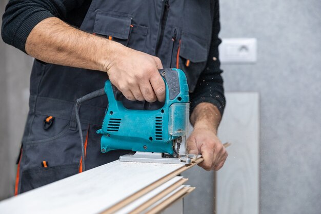 Man working with jigsaw on white wood laminate