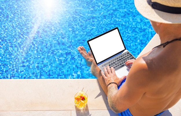 Man working with laptop computer by the pool