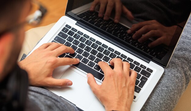 Photo man working with a laptop sitting on a sofa at home