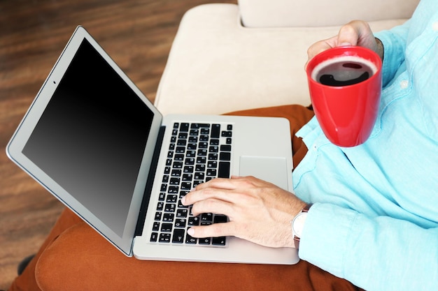 Man working with laptop on sofa in room