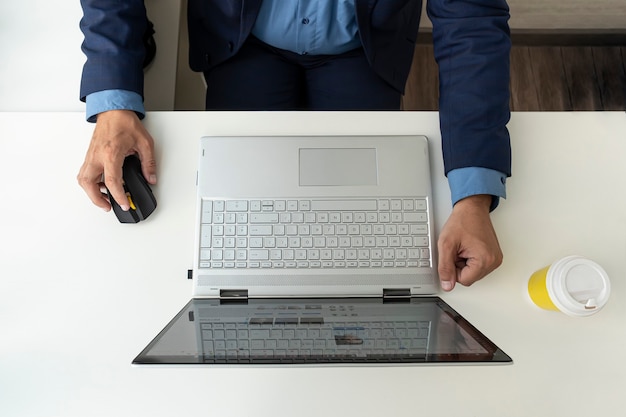 노트북으로 작업하는 남자, 상위 뷰입니다. 사무실에서 일하는 사업가. 흰 책상 위에 있는 컴퓨터와 재킷을 입은 매니저의 손.