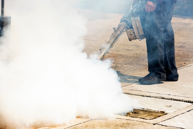 Man working with a smoke machine into manhole for pest control