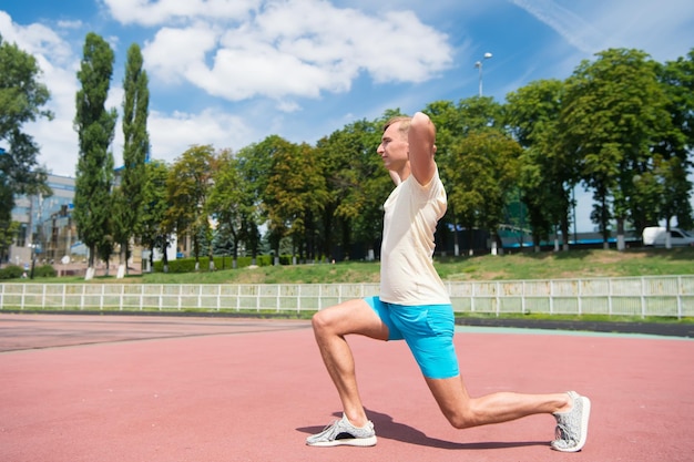 Мужская тренировка и растяжка на солнечном открытом воздухе на голубом небе, спорт и фитнес