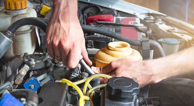 A man works in a garage. A man performs car repair and maintenance.