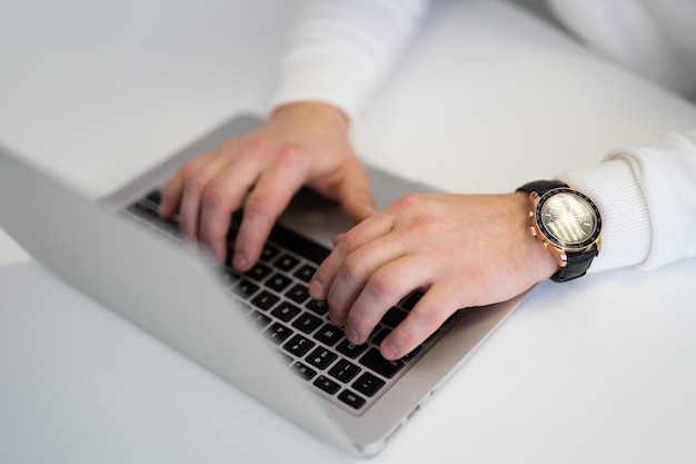 Foto un uomo lavora su un portatile in ufficio un primo piano di un orologio a mano e una tastiera