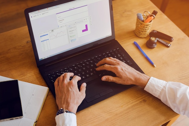 A man works on a laptop on a wooden desk