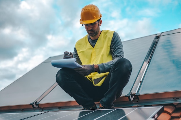 Man works on renewable energy system with solar panel for electricity and hot water