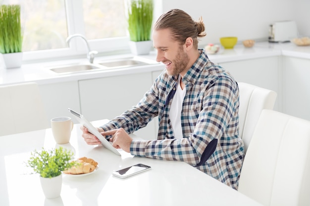 L'uomo lavora su tablet e mangia la colazione