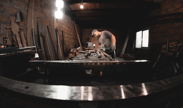 A man works with an angle grinder in his home workshop Making metal products with your own hands