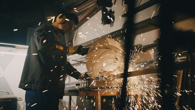 A man works with a circular saw Worker grinder grinds metal in workshop Sparks fly from hot metal