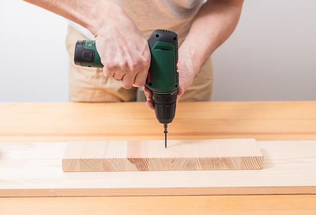 A man works with an electric screwdriver on a wooden table