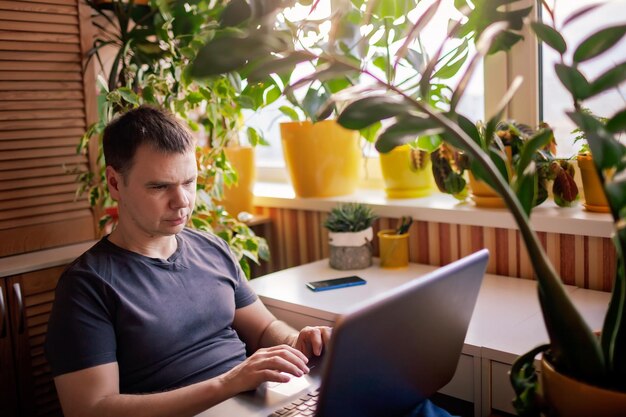 Photo man works with laptop remotely from home distant work place with green-nature inspired home office