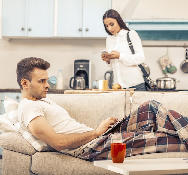 Man works with laptop stayingAt Home And lying on Sofa