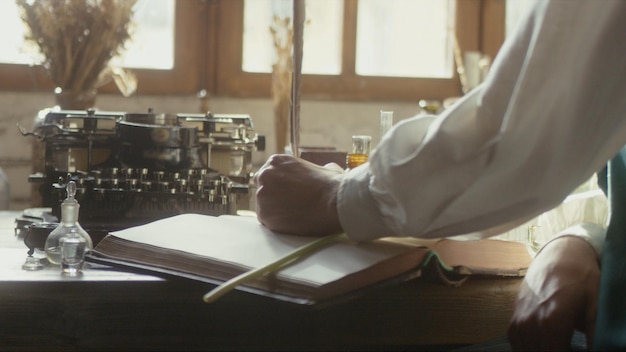 Uno scrittore intinge la penna in un calamaio e si prepara a scrivere un libro nella sua foto premium del laboratorio