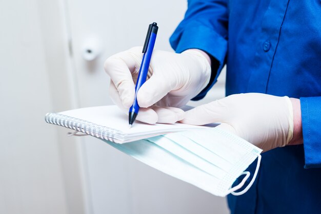 Man writes a note in a notebook during a coronavirus epidemic, wearing latex gloves