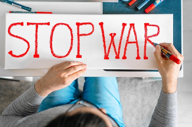 Photo man writing anti-war banner at home