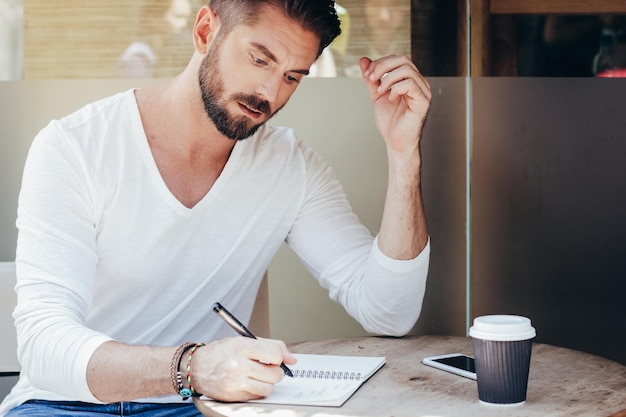 Man writing on book at cafe