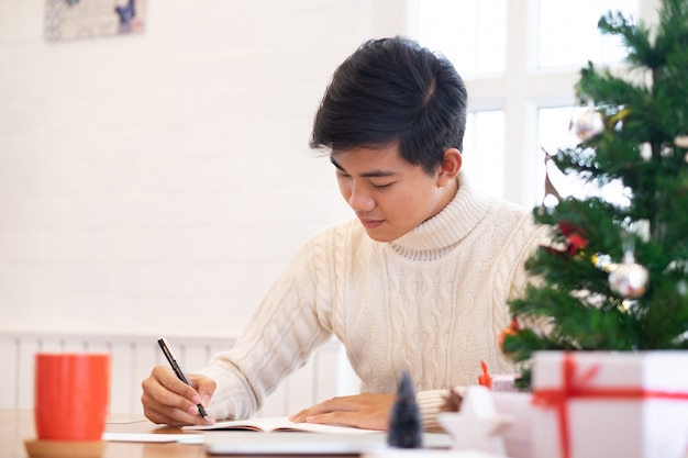 Man writing christmas and new year greeting cards.