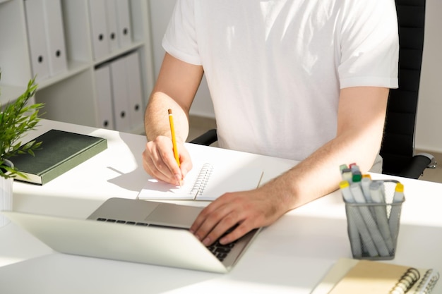 Man writing and using laptop