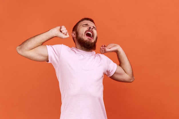 Man yawning and covering mouth with hand feeling exhausted lack of sleep outstretching arms