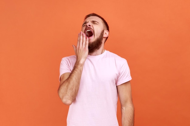 L'uomo sbadiglia e copre la bocca con la mano sentendosi esausto, mancanza di sonno