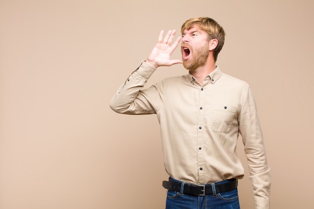 写真 横にスペースをコピーするために大声で怒って叫び、口の横に手を持つ男