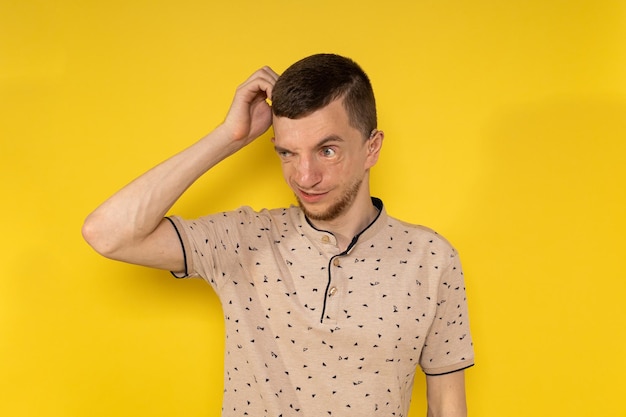 Man on yellow background scratching his head