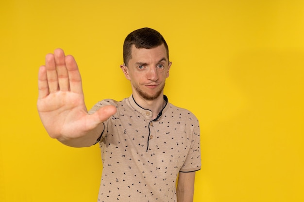 The man on the yellow background shows his feet with the palm of his hand