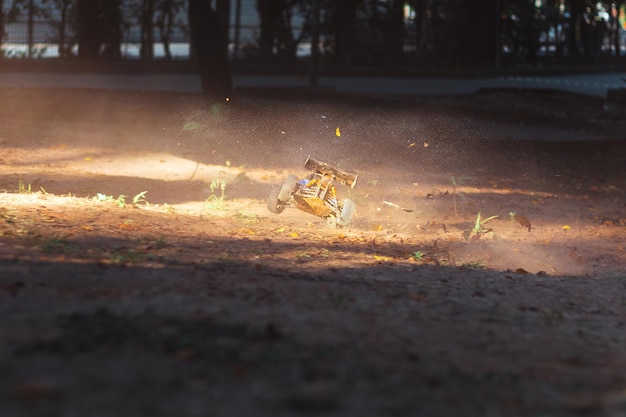 A man in a yellow bobcat suit is on the ground with a tree in the background.