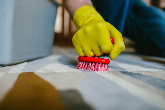 A man in yellow gloves washes the carpet