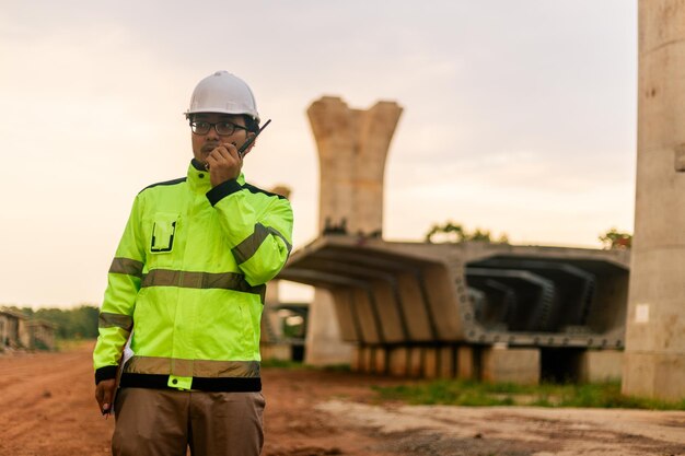 Foto un uomo con una giacca gialla sta scrivendo su un blocco mentre si trova di fronte a un ponte