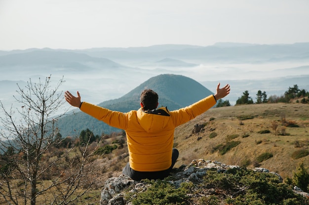 Photo man in a yellow jacket standing on the rock among the mountains at sunny day in the forest in turkey