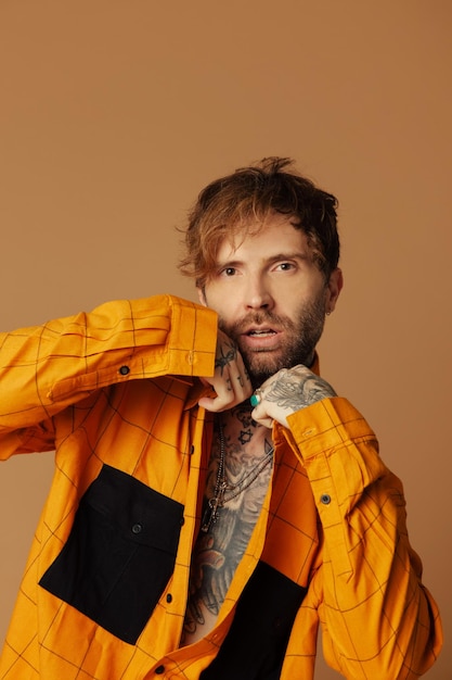 A man in a yellow jacket with tattoos on his arms