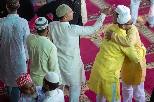 Photo a man in a yellow shirt is hugging another man in a crowd.