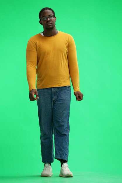 Photo a man in a yellow sweater on a green background in full length