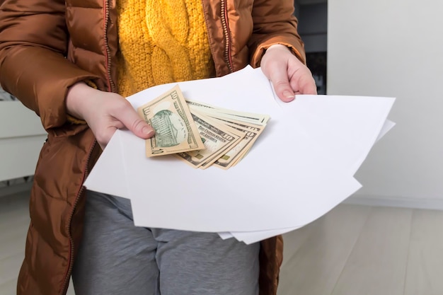 A man in a yellow sweater and jacket with documents in his hands and money The concept of the economic crisis and large utility bills in homes