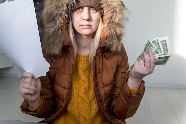 Foto un uomo con un maglione giallo e una giacca con documenti in mano e denaro il concetto di crisi economica e grandi bollette nelle case