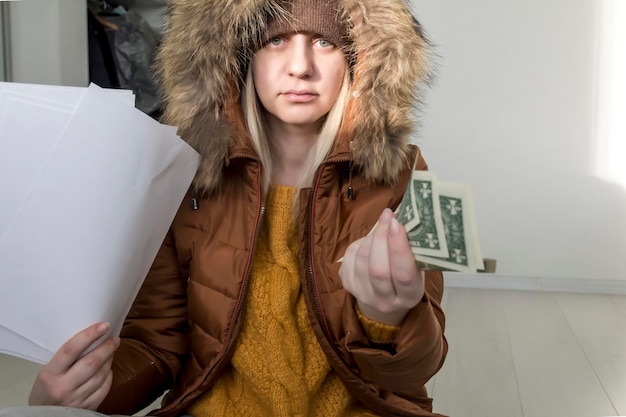 Photo a man in a yellow sweater and jacket with documents in his hands and money the concept of the economic crisis and large utility bills in homes