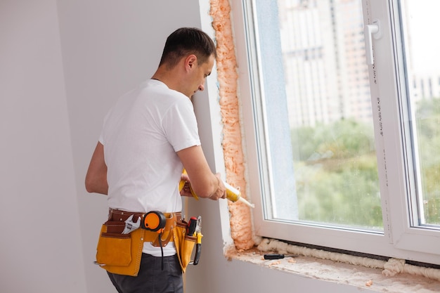 Man zet vulling tussen raam en muur in een nieuw huis