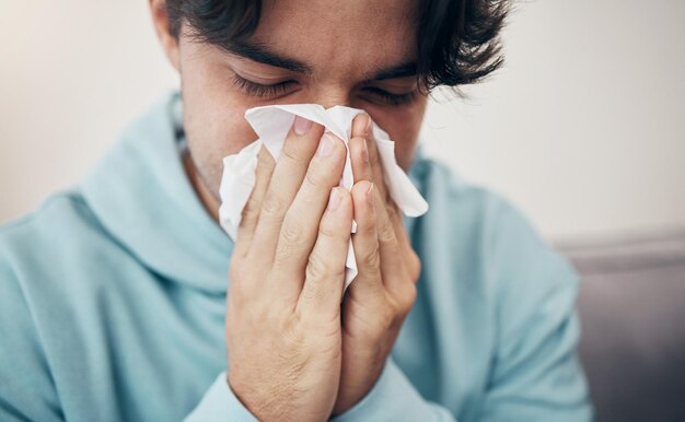 Man ziek en bank met weefselziekte en virus voor infectie sinus- en verkoudheidssymptomen Niezen snuitende neus en allergie in de bank in de woonkamer hooikoorts en gezondheidszorg voor ziektekoorts of alleen