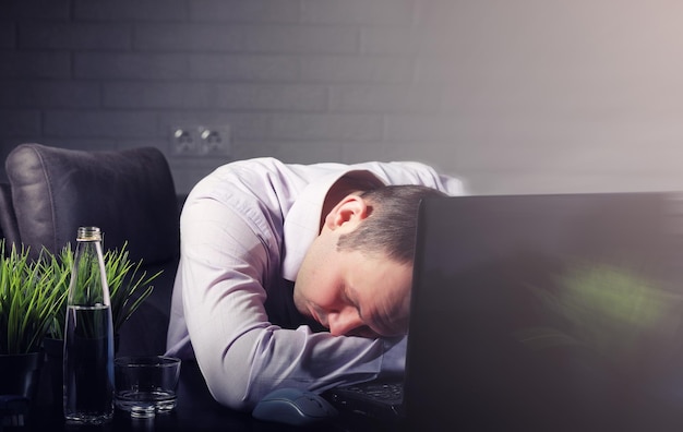 Foto man zit aan tafel en werkt op laptop