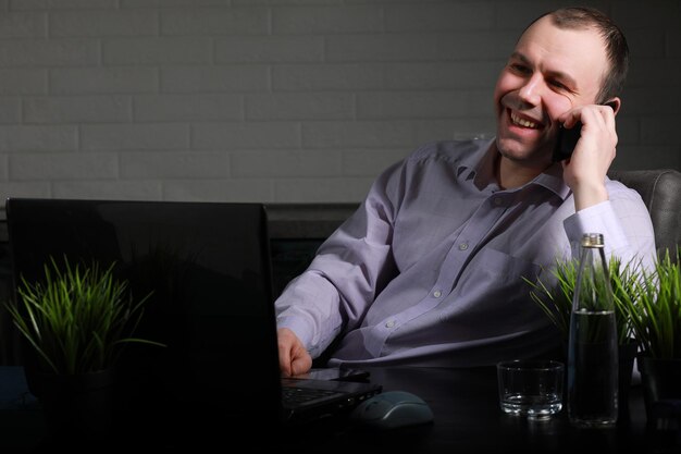 Man zit aan zijn bureau en werkt op een laptop